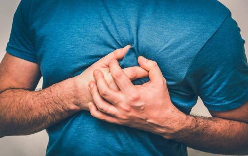 A man clutching his chest as he experiences symptoms of a heart attack